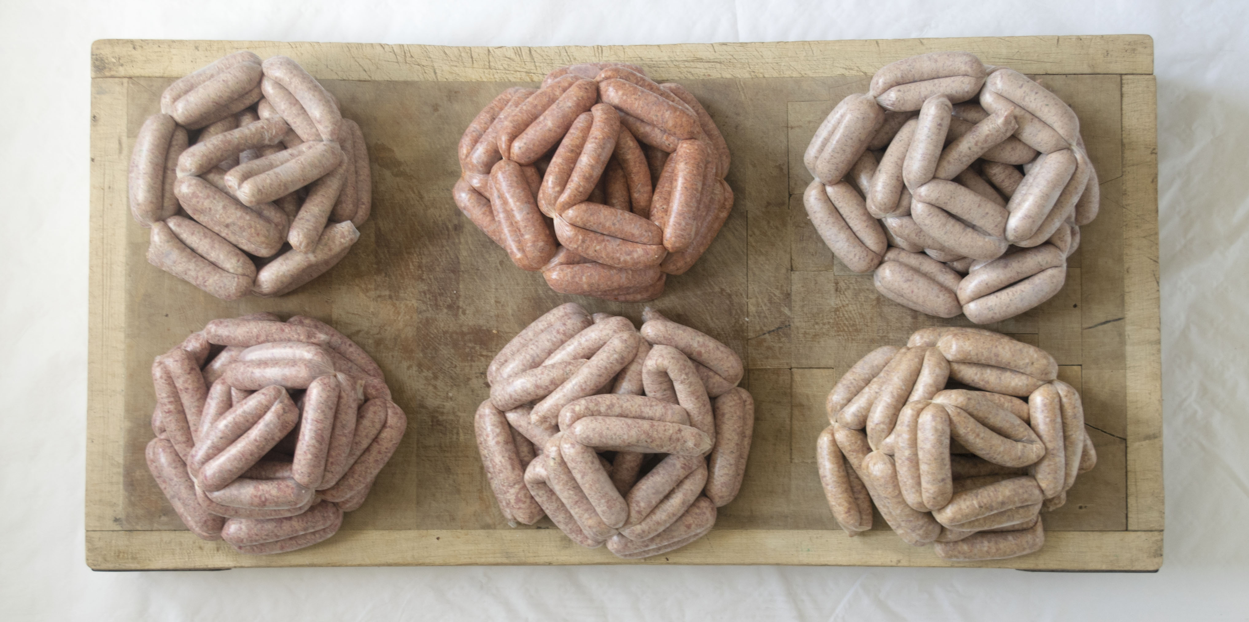 Homemade Sausages on a butchers block, Cumberland, Sun-dried Tomato, Apple and Cider, Pork, Lamb, Hot Paprika and Garlic